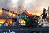 Libyan rebels celebrate at Bab Al-Aziziya compound as a large tent burns in background