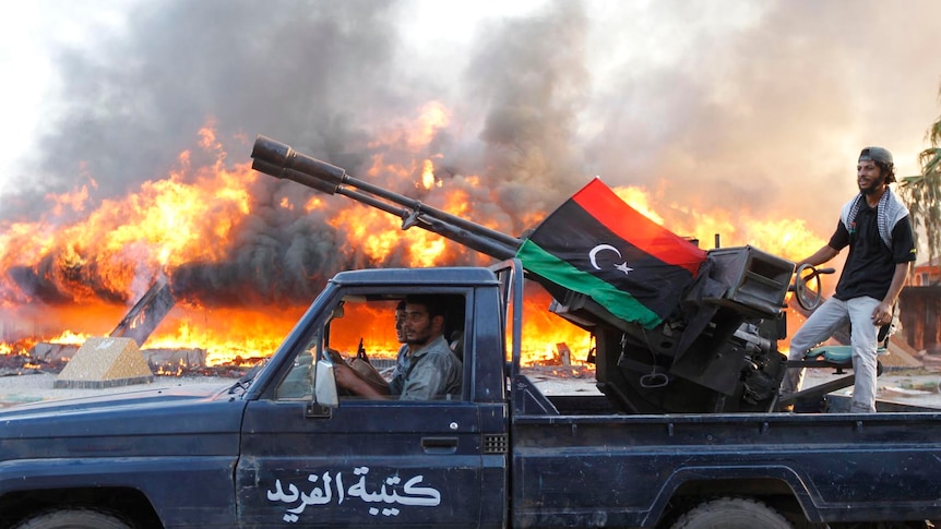 Libyan rebels celebrate at Bab Al-Aziziya compound as a large tent burns in background