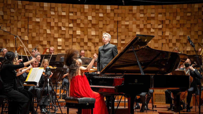 Yeol Eum Son seated at the Steinway playing her last notes, she is dressed in red and her hair flying back.
