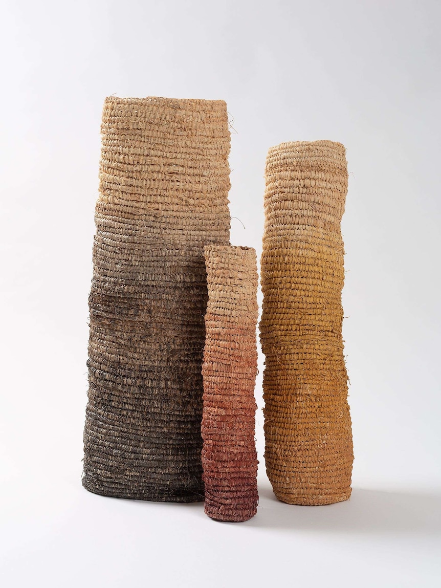 Three woven poles decorated with different natural paints and inks.