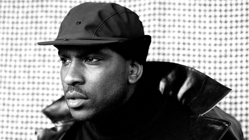 Black and white closeup image of Skepta, wearing a hat.