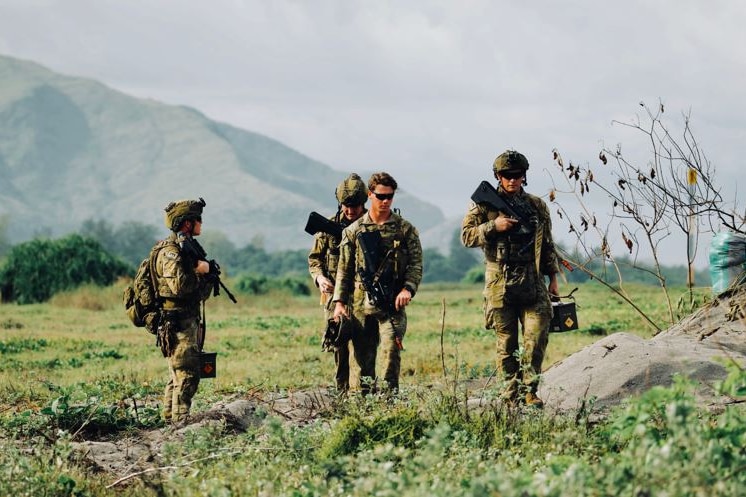 A group of soldiers walk across barren land.