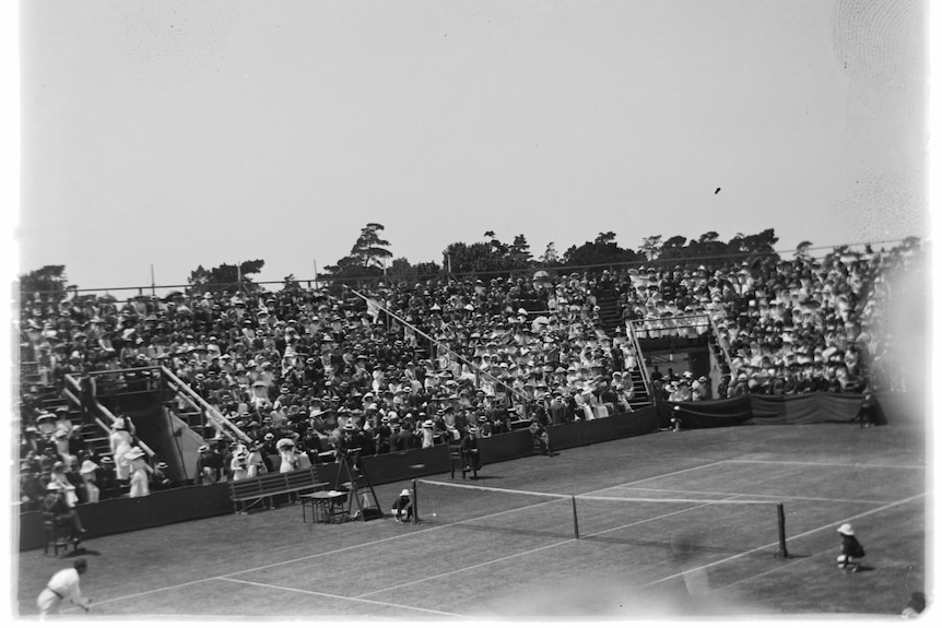 Old photo of tennis matches being played in front of grandstands full of spectators