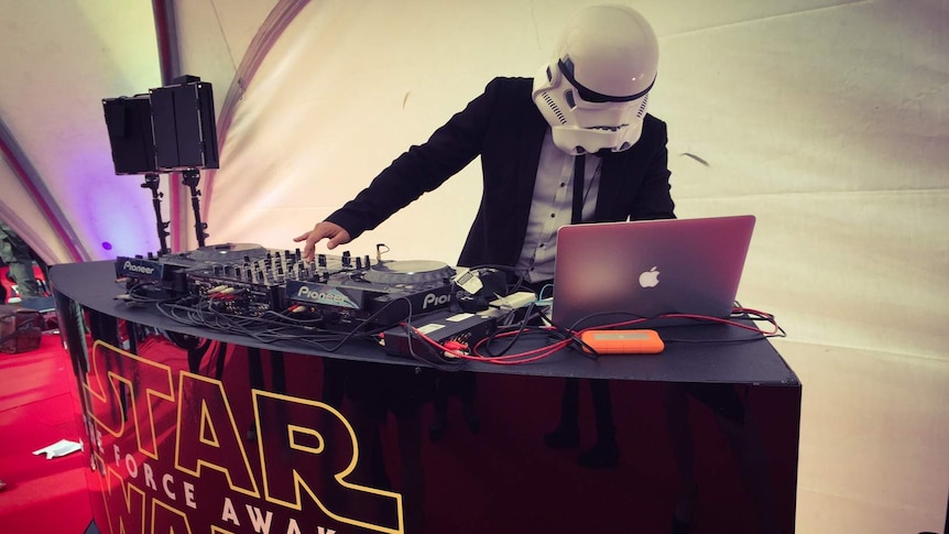 A DJ, wearing a stormtrooper helmet, plays music at the premiere of Star Wars: The Force Awakens.