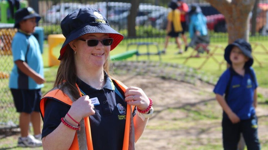 Teenage girl in hat and sunglasses in playground with other children at a primary school
