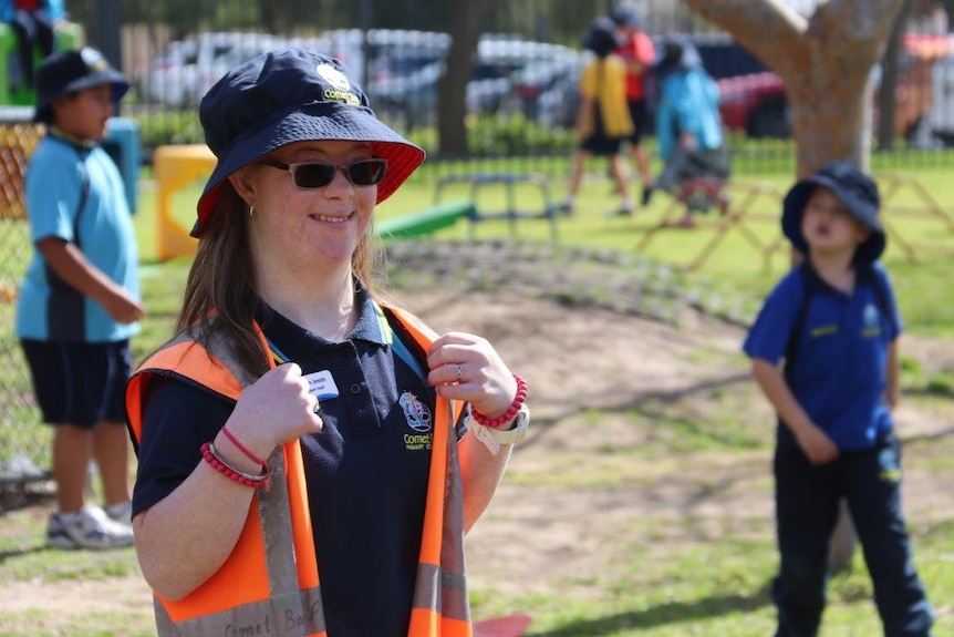 Teenage girl in hat and sunglasses in playground with other children at a primary school