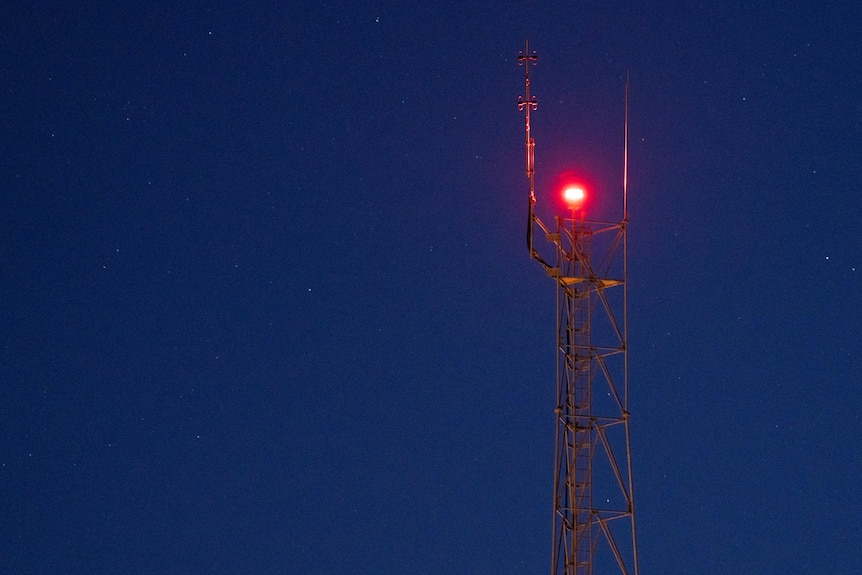 A mobile phone tower pictured against a blue sky at dusk