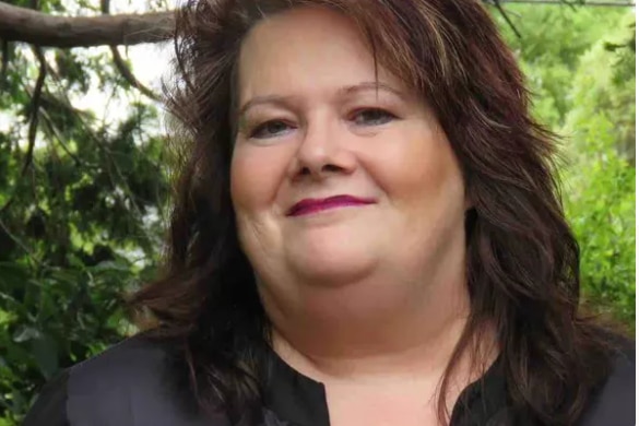 Woman with pink lips smiles at camera.