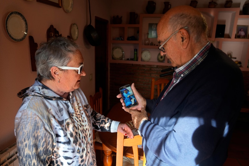 Santiago Sánchez's parents look at a photo of their son on a smartphone. 
