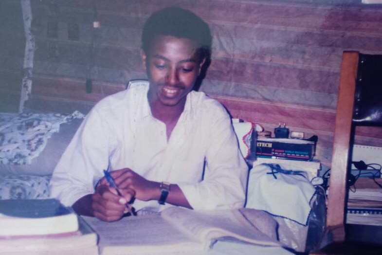 Girma Adane leans over a text book on a desk reading