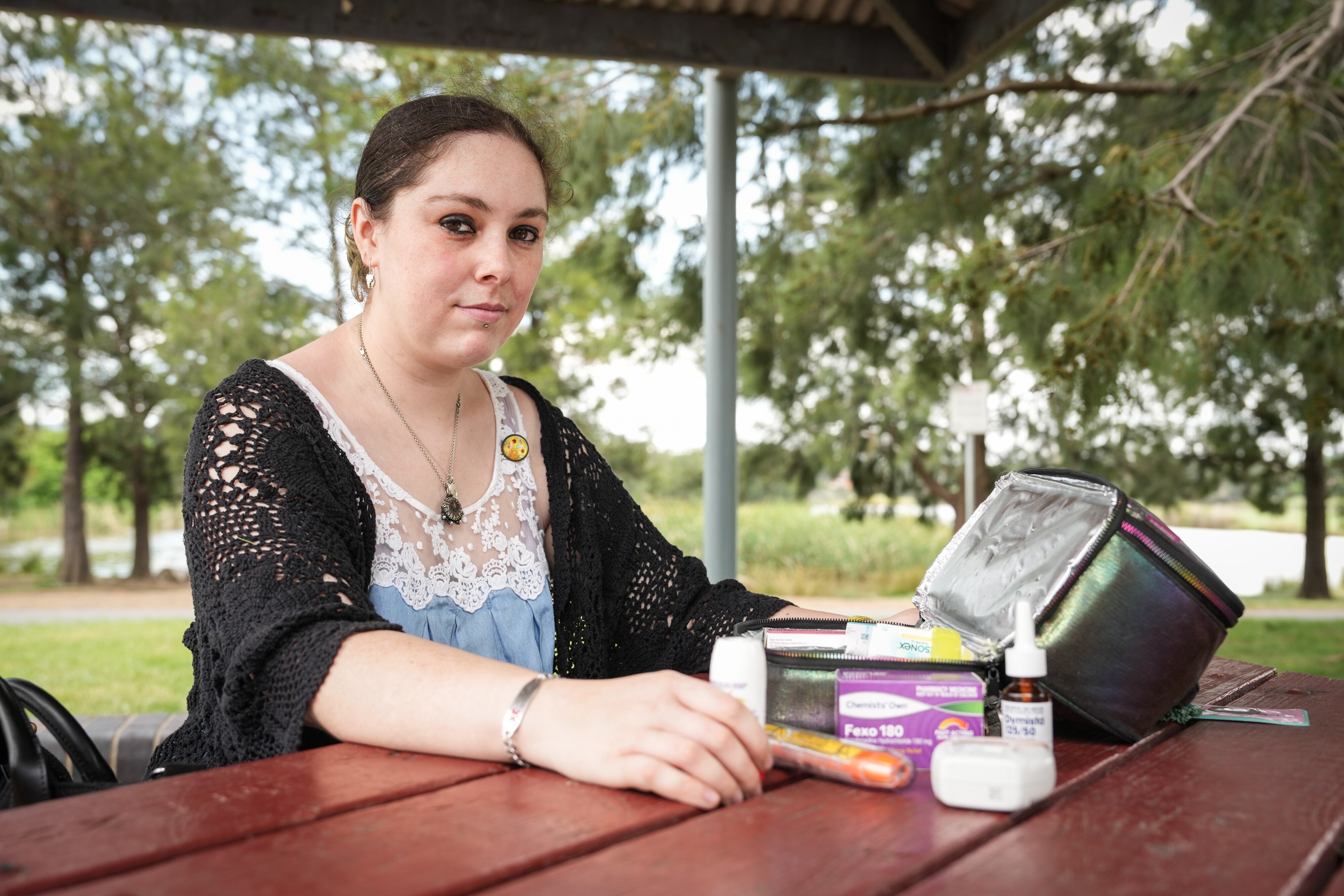 A young woman sitting at a table with a bag of medications.