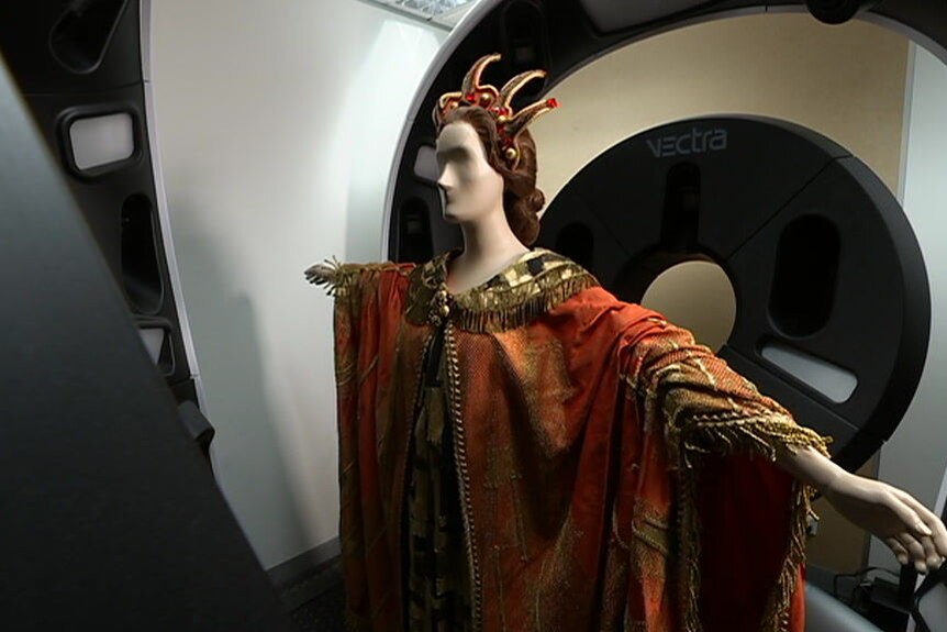 A mannequin with an orange opera costume is scanned in large medical scanner.
