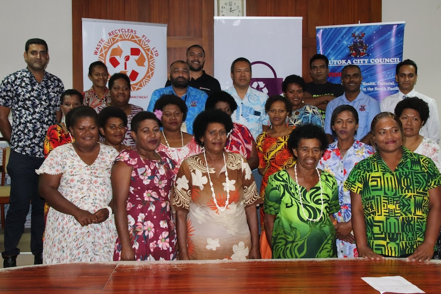 A group of people, mainly women, pose for a photo in front of a board table. 