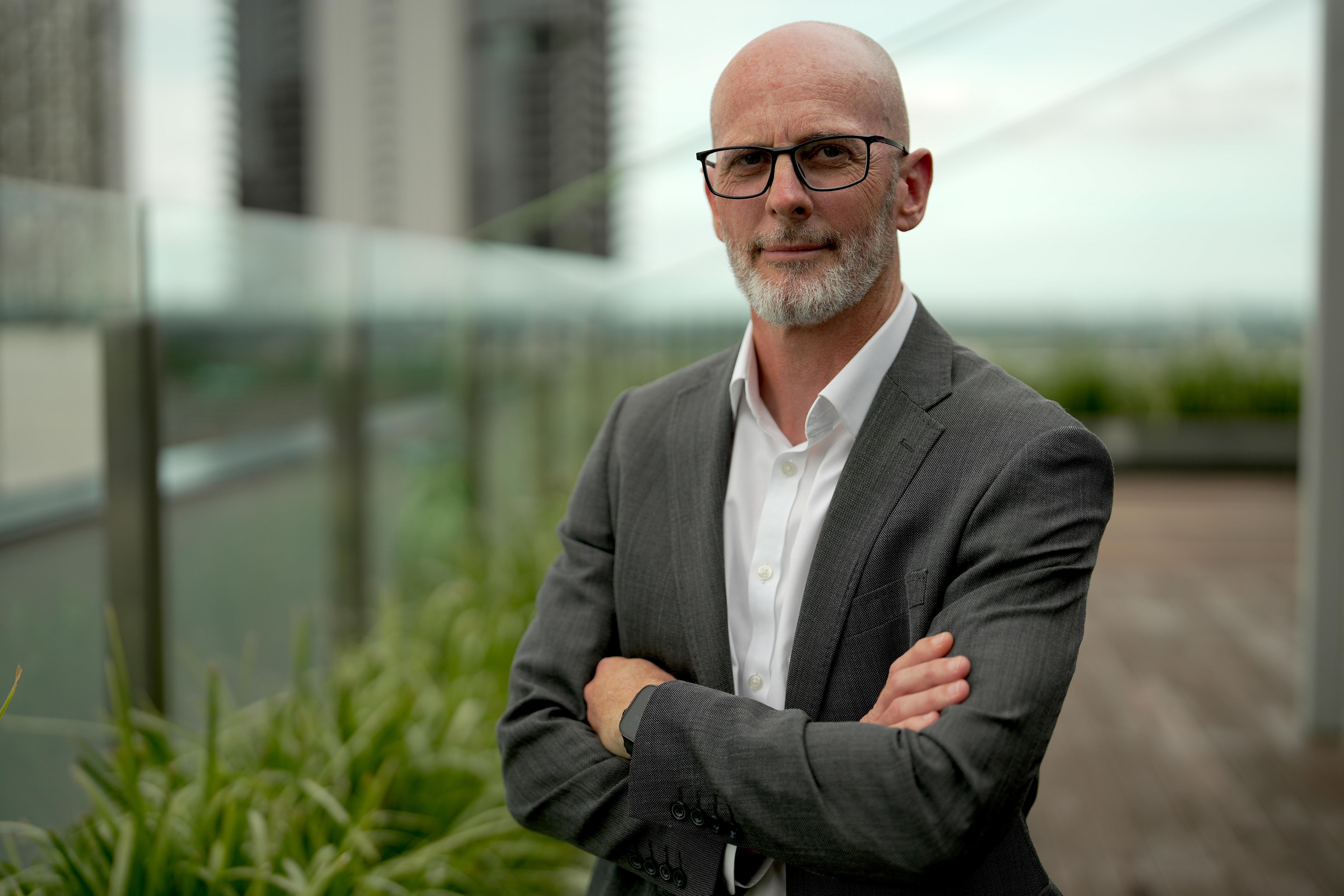 Um homem de terno com os braços cruzados.