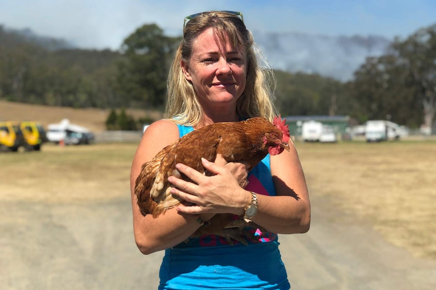 A woman smiles while clutching a rooster