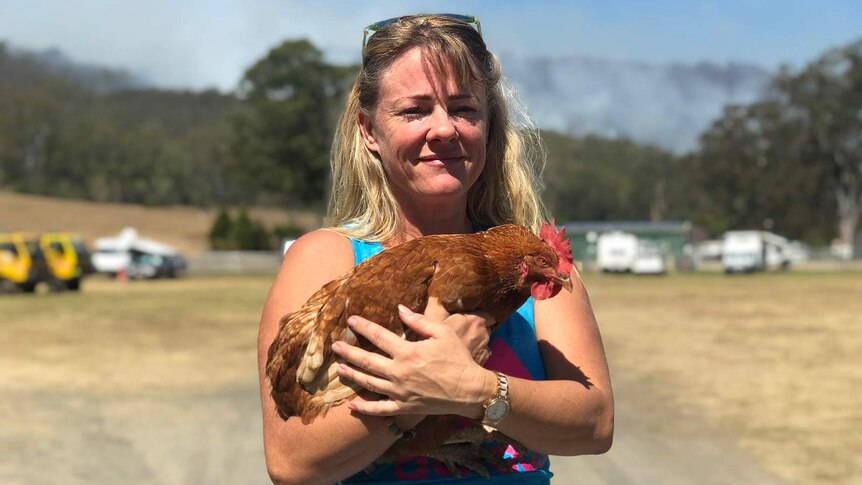 A woman smiles while clutching a rooster