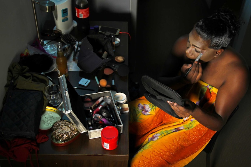 An aerial photo of a Tiwi Islands drag queen applying make-up to her face.