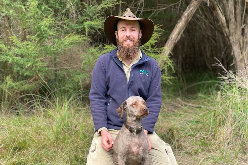 Nick Rutter crouching down with his dog Daisy. 