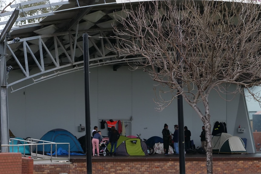 A wide, distant shot of a group of tents on a stage in a park, in the middle of Bunbury