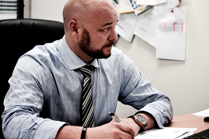 Defence lawyer Marty Aust sits at his desk looking worried.