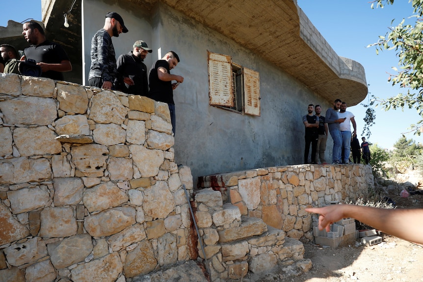 People mill around the scene where three Palestinians were shot by Israeli forces in the West Bank.