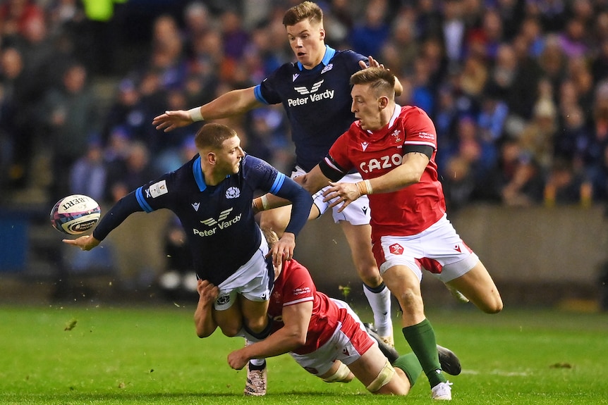 Finn Russell flicks the ball out the back of the hand as he his tackled