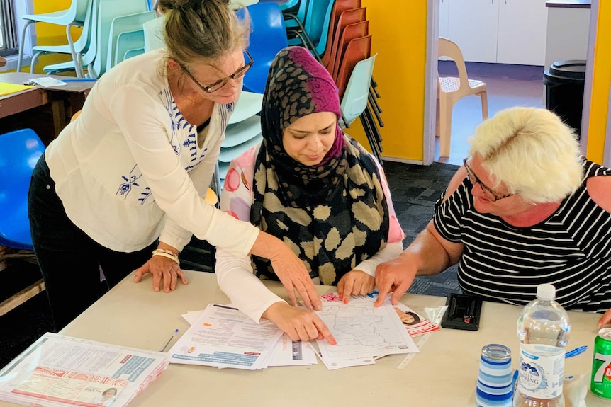 Three women around a table looking at papers