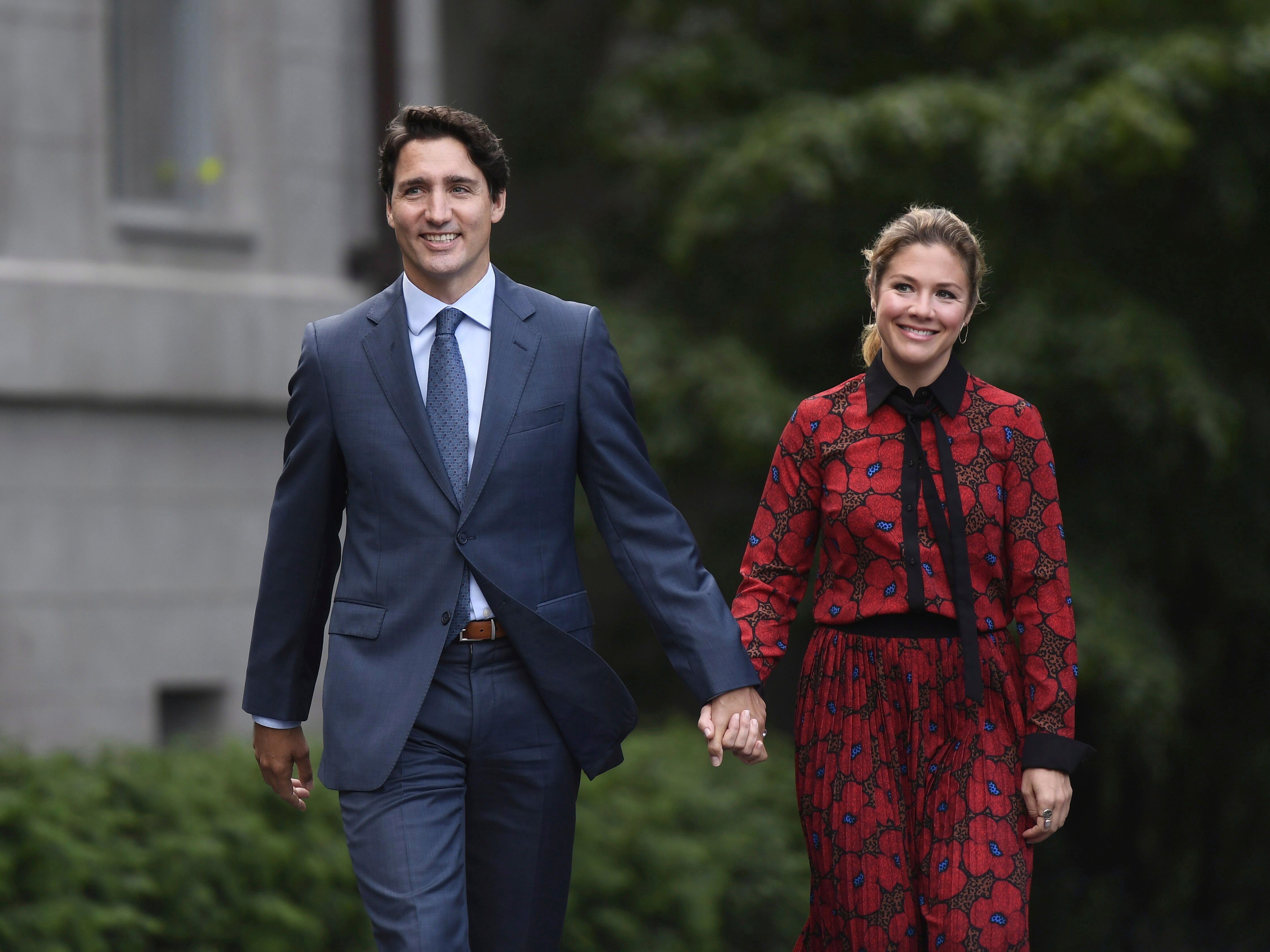 Man in blue suit holds hand of woman in red and black dress 