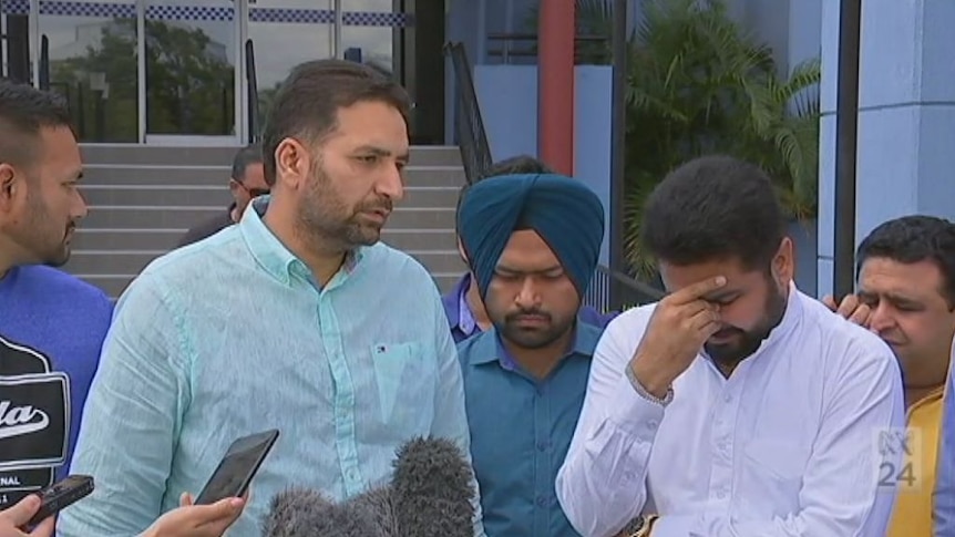 Members of the Indian community, including Manmeet Alisher's brother Amit (on the right) speak to the media
