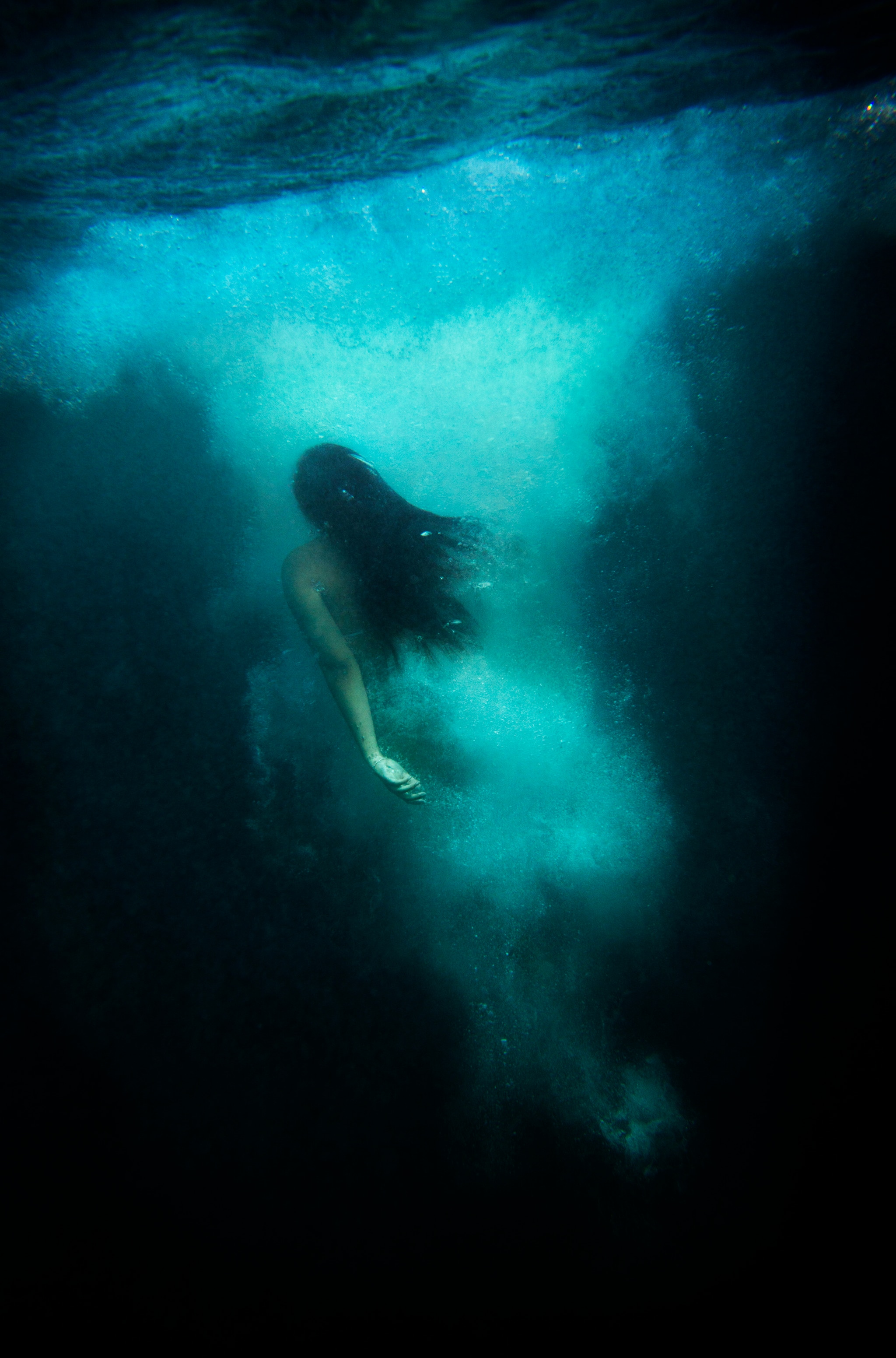 Image by Narelle Autio of a female figure swimming underwater up towards the surface, surrounded by bubbles