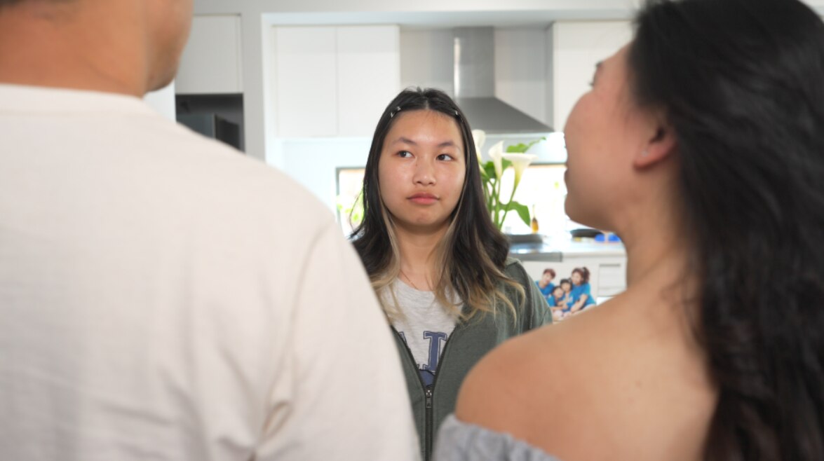 A young person speaking to two adults