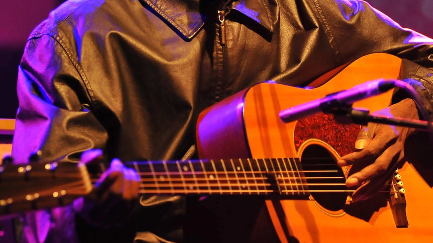 Close-up of man's hands playing the guitar on stage.