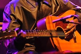 Close-up of man's hands playing the guitar on stage.