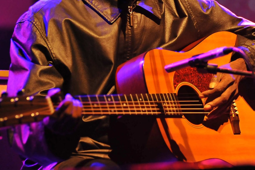 Close-up of man's hands playing the guitar on stage.