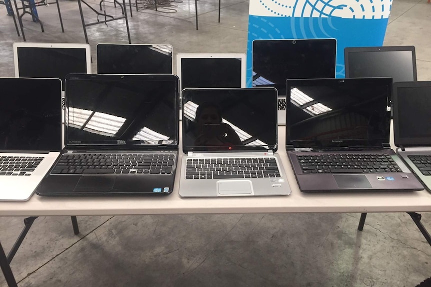 Laptops, up for auction, are displayed on a table.