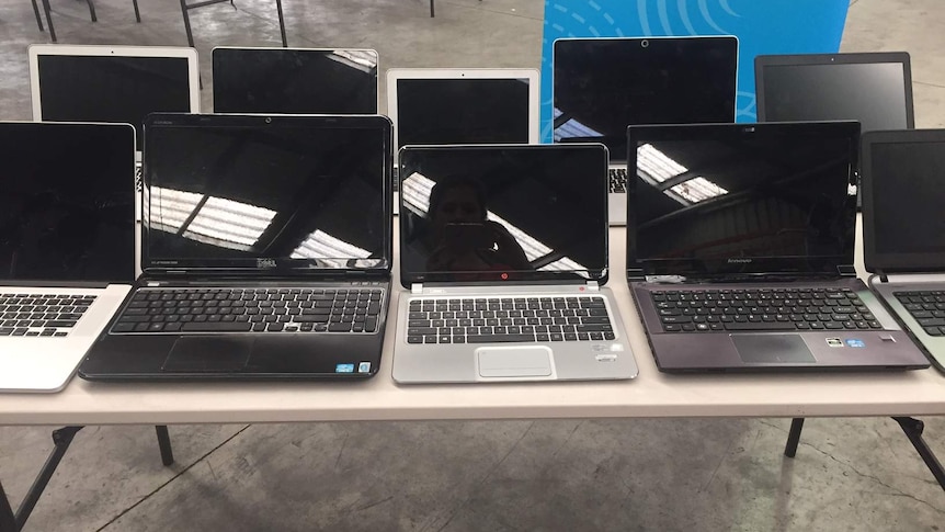 Laptops, up for auction, are displayed on a table.