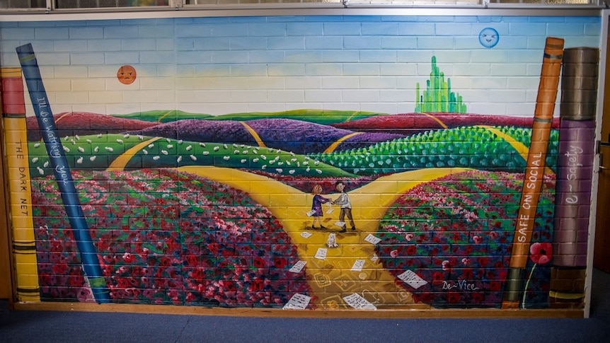A painted picture of two children on the yellow brick road on a brick wall of a school building