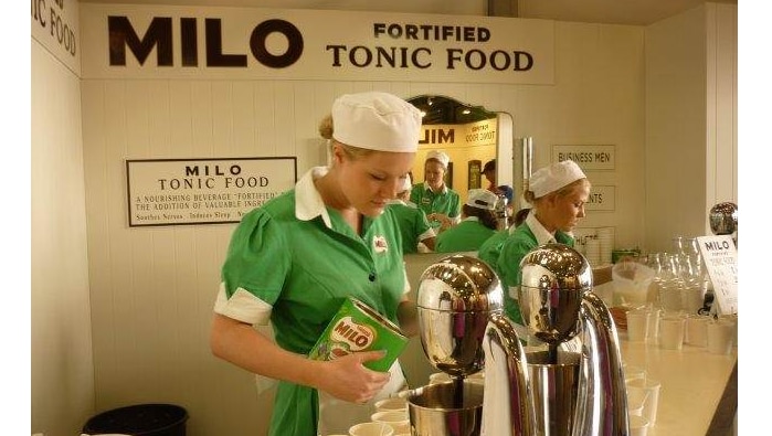 Two young women making milkshakes under a Milo Fortified Tonic Food sign.