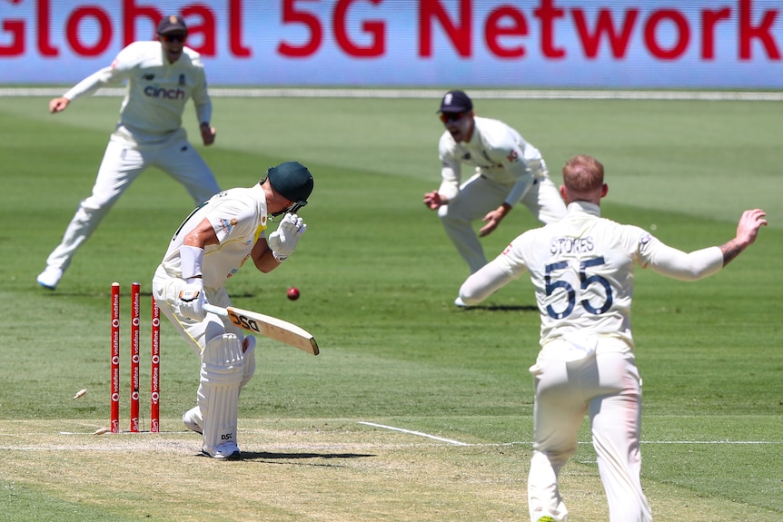 Australia batter David Warner looks back at his stumps after being bowled off a no ball by Ben Stokes (right).