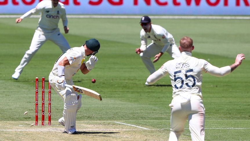 Australia batter David Warner looks back at his stumps after being bowled off a no ball by Ben Stokes (right).