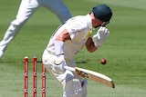 Australia batter David Warner looks back at his stumps after being bowled off a no ball by Ben Stokes (right).