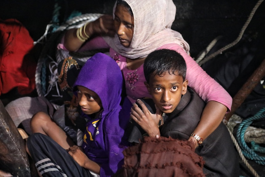 Madre e hijos rohingya desembarcan del barco.