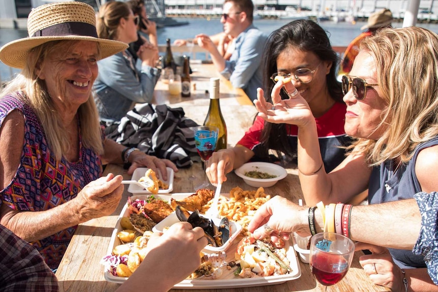 Table of women enjoying food in outdoor setting.