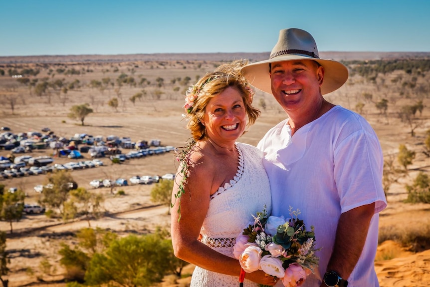 A couple smile after being married in an outback setting.