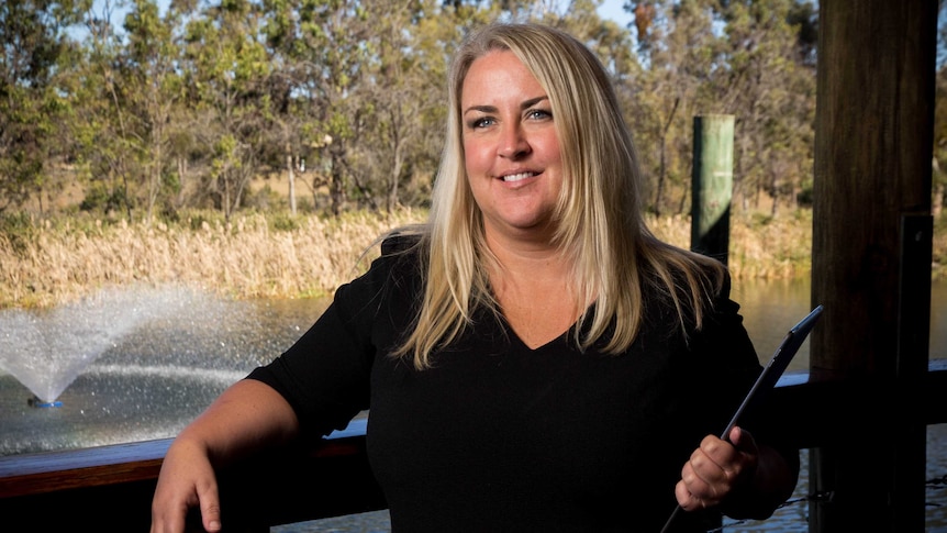 Kate Cooper leans on a railing holding an iPad.