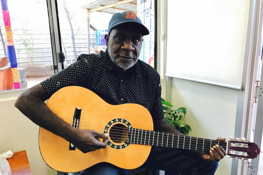 Dialysis patient, Quentin Jurrah sitting down playing a guitar