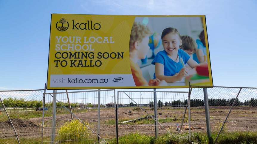 A billboard in an empty paddock for a new school at Kalkallo.