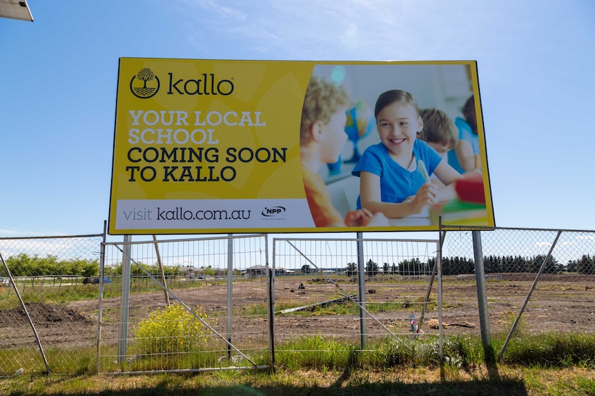 A billboard in an empty paddock for a new school at Kalkallo.