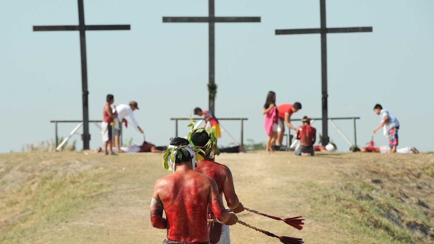 Penitents walk towards crosses as they flagellate themselves