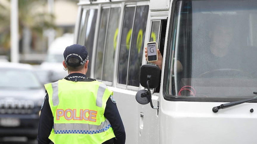A driver from NSW displays his permit to Police at Griffith Street checkpoint at Coolangatta on the Gold Coast.